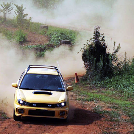 sweet af image of a yellow Subaru WRX being drifted around a dirt course